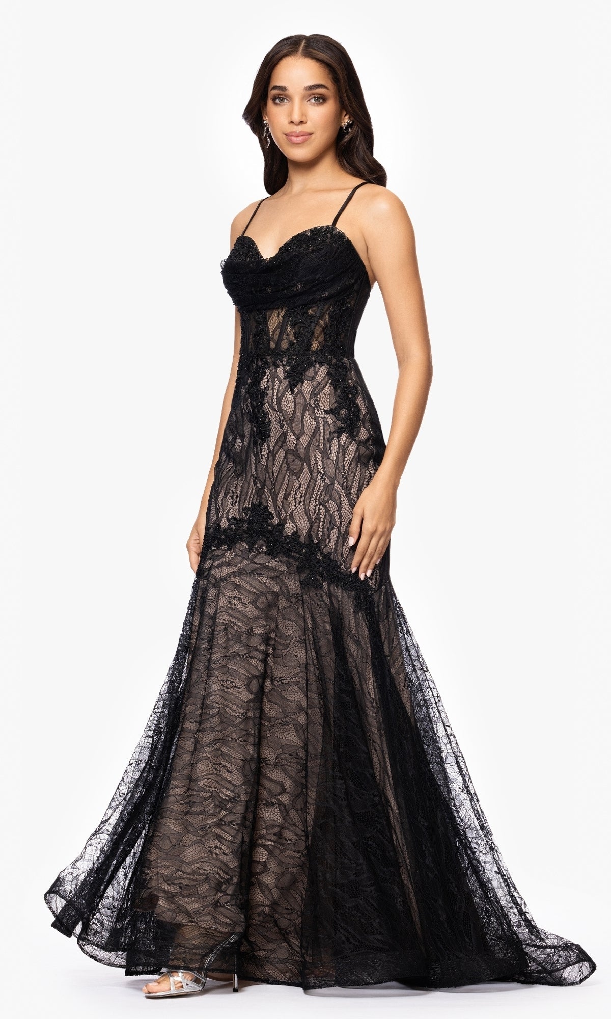A woman models the Long Black Lace Prom Dress: Blondie Nites 5463BN, a sleeveless, floor-length mermaid gown with sheer lace details and spaghetti straps, posing against a plain white background.