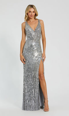 A woman models the Mac Duggal 5473 sleeveless beaded formal dress, featuring a V-neckline and thigh-high slit, against a plain light background.