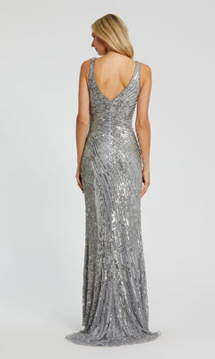 A woman with straight blonde hair stands facing away against a plain light background, wearing the Mac Duggal 5473 Sleeveless Beaded Formal Dress featuring shimmering beads and a V-shaped back.