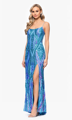 A woman models the Blondie Nites 5493BN long blue sequin prom dress, featuring spaghetti straps and a high leg slit, against a plain white background.