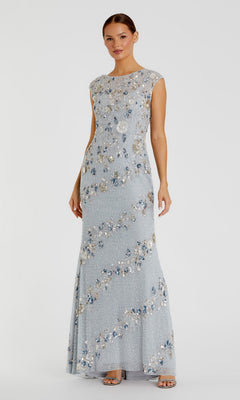 A woman stands in the Mac Duggal 5500 Beaded Long Formal Dress, a floor-length, light blue gown with floral sequin embellishments and cap sleeves, paired with open-toe heels against a plain light background.