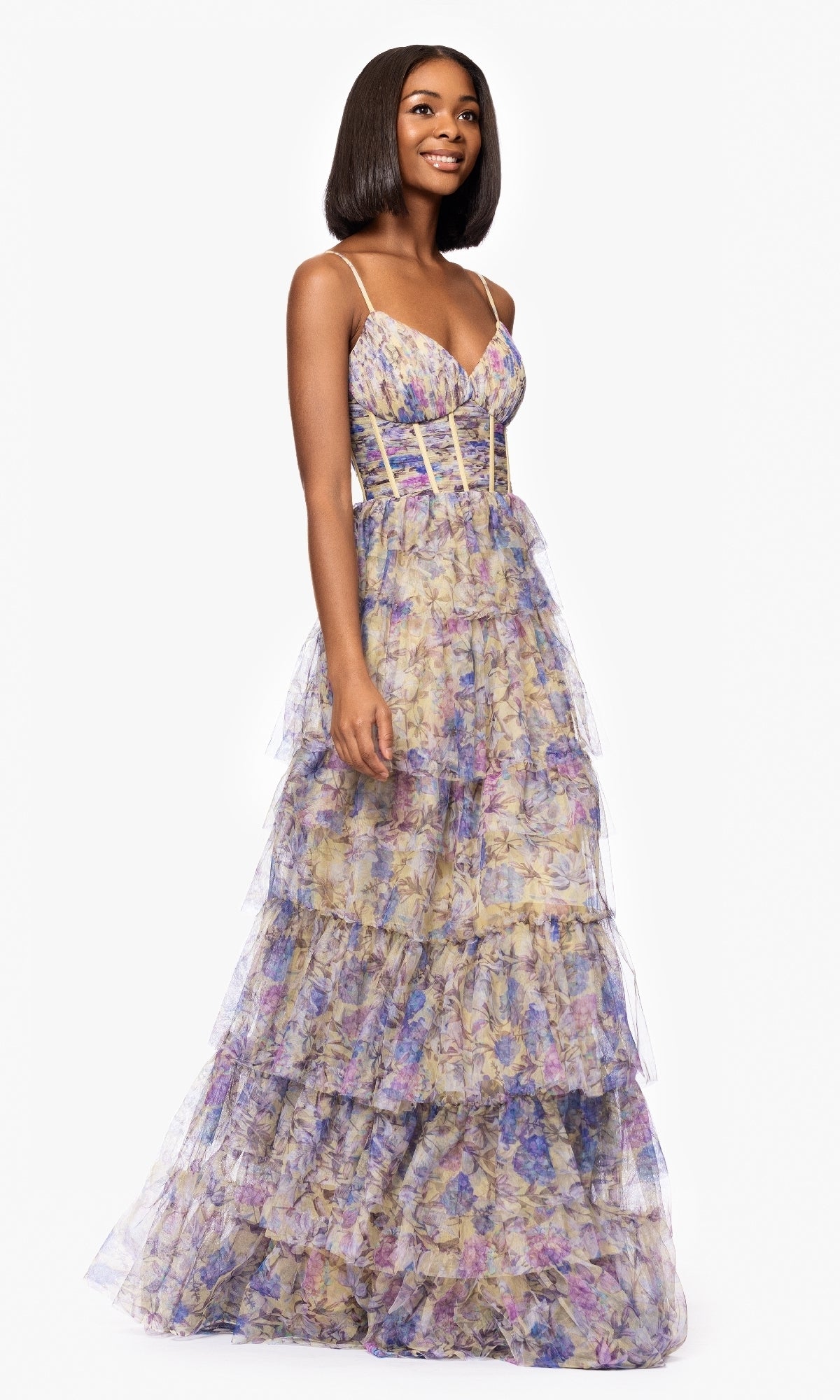 A woman stands against a white background wearing the Blondie Nites 5500BN Floral-Print Long Prom Dress, featuring a sleeveless design, fitted bodice, spaghetti straps, and floor-length floral print.