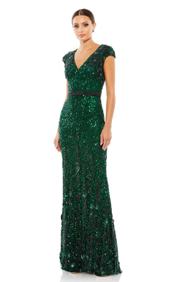 A woman wears the Long Formal Dress 5505 by Mac Duggal, a floor-length dark green beaded gown featuring short sleeves, a bra-friendly V-neckline, and fitted waist, standing against a plain white background.