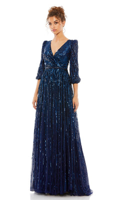 A woman wearing the Mac Duggal 5509 long sleeve formal dress in navy blue with a sequin finish, V-neckline, and fitted waist stands against a white background.