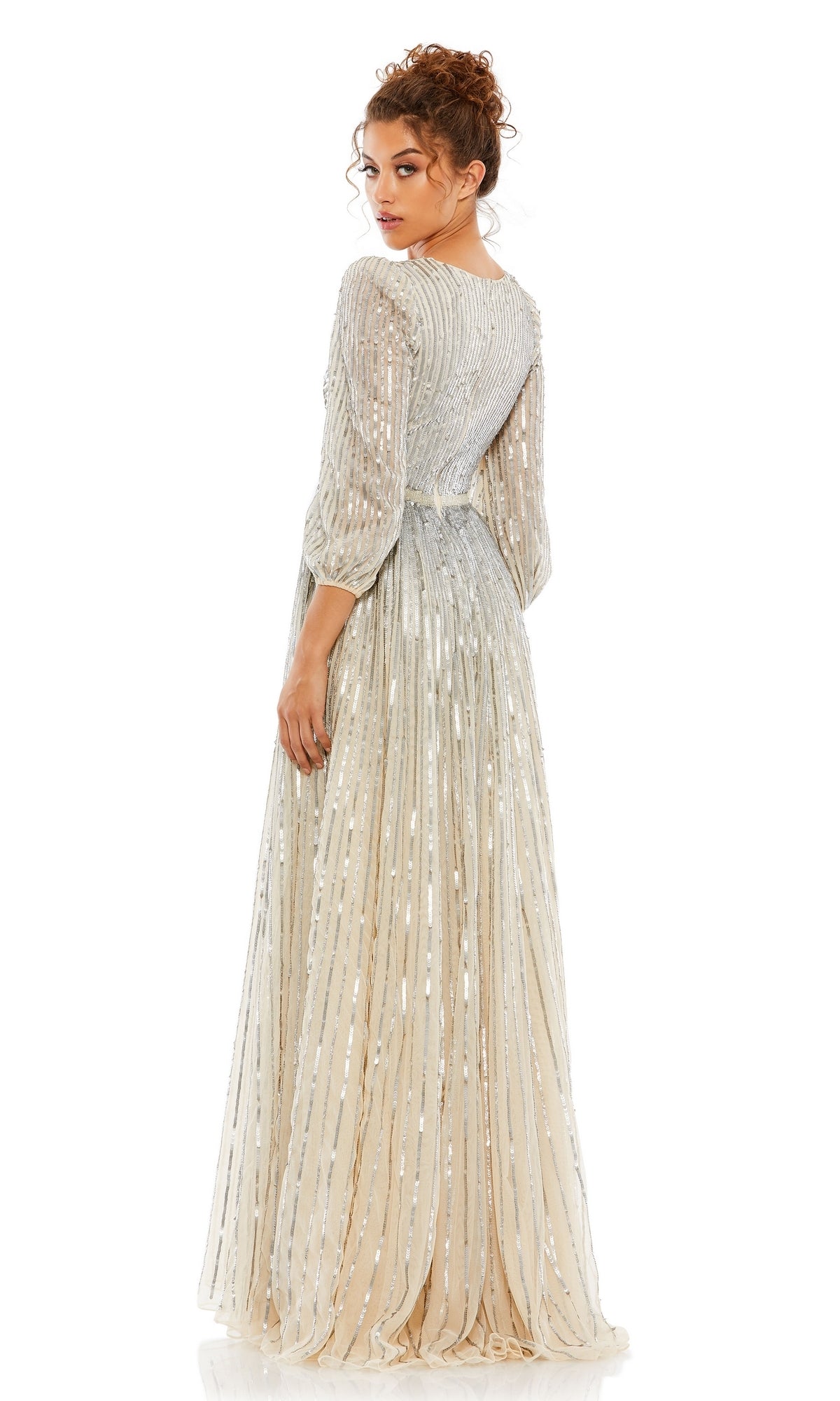A woman stands against a white background, looking over her shoulder while wearing the Mac Duggal 5509 long sleeve formal dress.