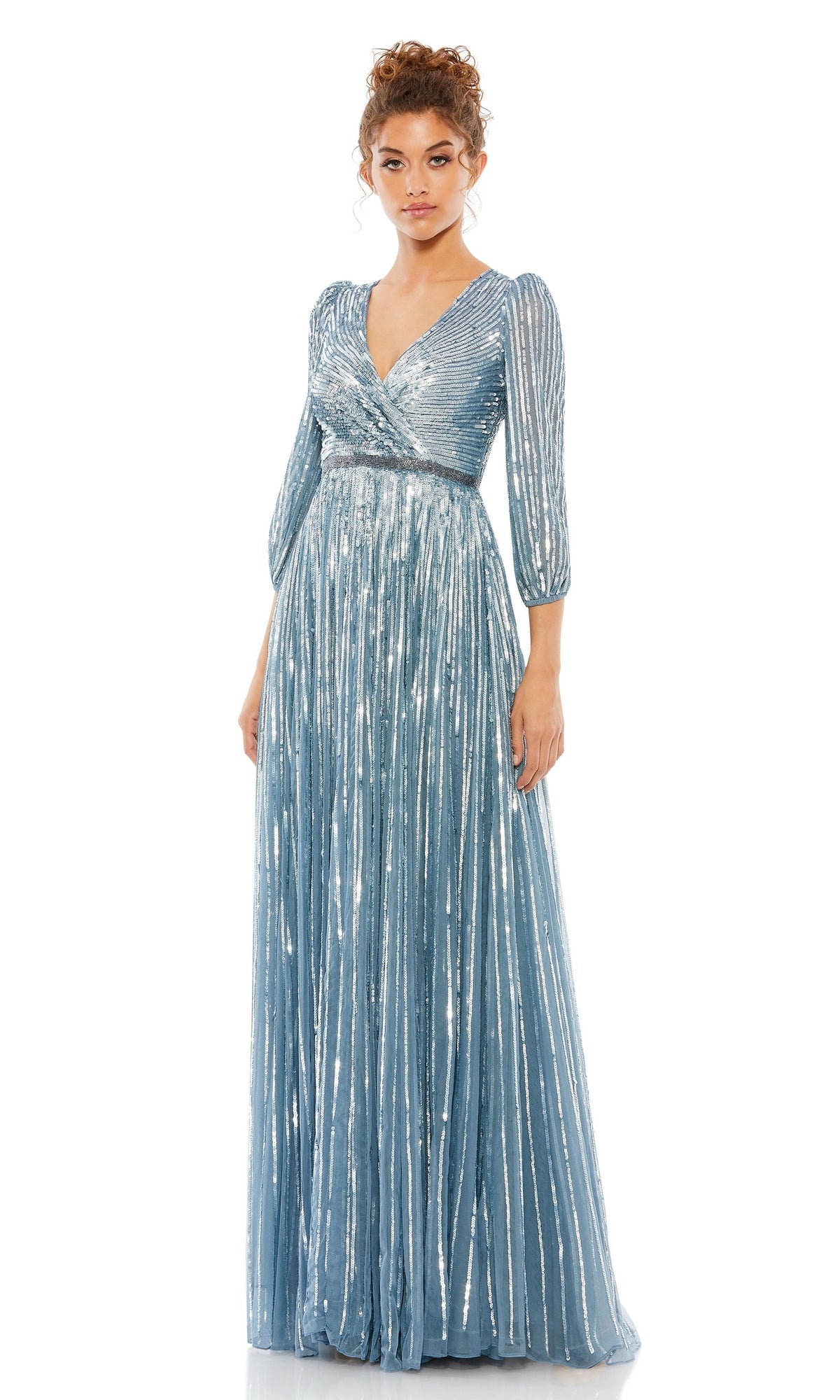 Woman wearing the Mac Duggal 5509 Long Sleeve Long Formal Dress in light blue with a shimmery finish, V-neckline, and pleated skirt, standing against a plain white background.