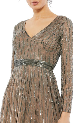 A woman wears the Short Semi-Formal Dress 5528 by Mac Duggal—an A-line, tea-length dress featuring long sleeves, a V-neckline, vertical metallic sequins, and a fitted sparkly belted waist.