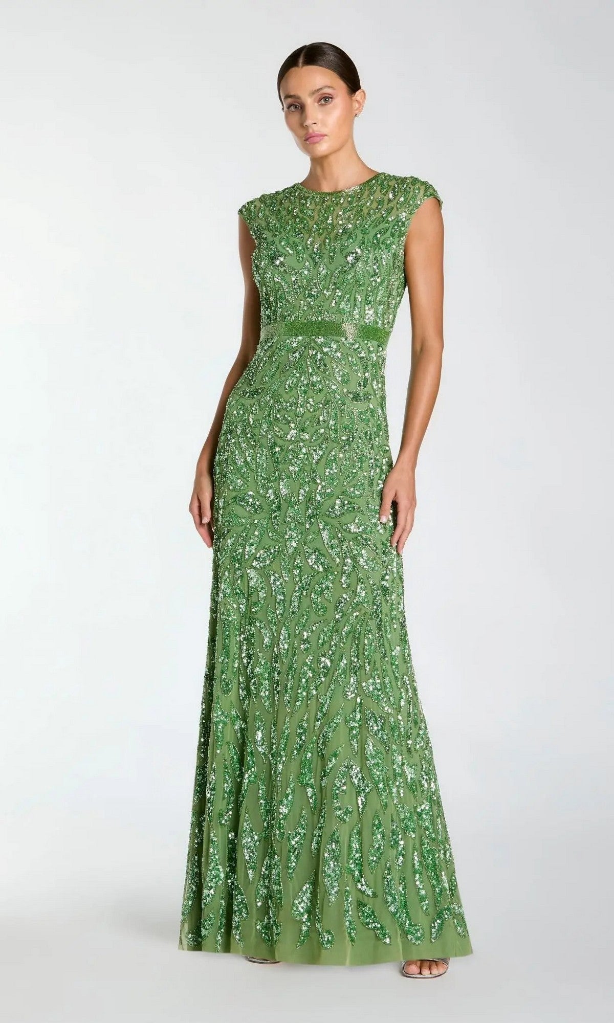 A woman wears the Mac Duggal 5532, a silver long sequin formal dress, featuring dazzling embellishments, standing against a plain light background.