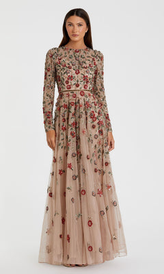 A woman models the Mac Duggal 5533 Beaded Long Sleeve Formal Dress, featuring colorful floral embroidery and a floor-length beige design, standing against a plain white background.