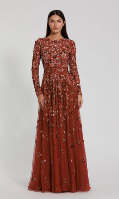 A woman stands facing forward wearing the Mac Duggal 5533 Beaded Long Sleeve Formal Dress—a floor-length, rust-colored gown featuring intricate floral embroidery.