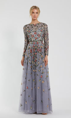 A woman showcases the elegance of the Mac Duggal 5533 Beaded Long Sleeve Formal Dress, featuring a floor-length silhouette and multicolored floral embroidery, standing against a plain light background.
