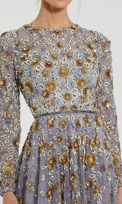 A close-up of a person wearing the Mac Duggal 5533 Beaded Long Sleeve Formal Dress, featuring sheer lavender fabric and gold and silver floral embellishments for an elegant, formal look.