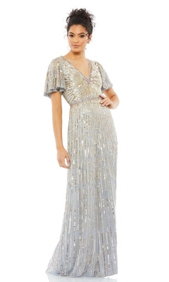 A woman stands wearing the Long Formal Dress 5538 by Mac Duggal, a floor-length light blue sequin gown with a V-neckline, gold and silver embellishments, and elegant short butterfly sleeves.