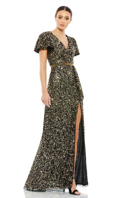 A woman wears the Mac Duggal 5540 Short-Sleeve Sequin Formal Dress—a black, floor-length gown with gold sequins, v-neckline, belted waist, high slit—paired with black heels.