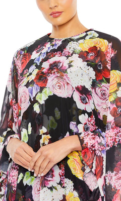 A person wears the Mac Duggal 55404 Short Print Cape Hoco Dress in black mesh with vibrant floral prints—an ideal inspiration for a chic, floral homecoming dress.