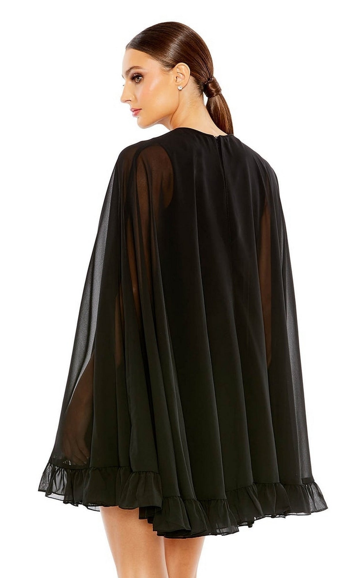 A woman with brown hair in a low ponytail is seen from the back at an angle, wearing the Mac Duggal 55407 Cape-Sleeve Short Ruffled Party Dress, featuring sheer black fabric and a ruffled hem.