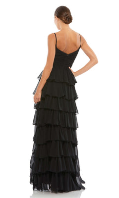 A woman stands with her back to the camera, hair in a neat bun, wearing the Mac Duggal 55416 Ruffled Long A-Line Prom Dress—sleeveless and elegant in black.