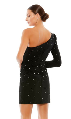 A woman faces away from the camera in a Mac Duggal 55667 Short Black Pearl Hoco Dress—one-shoulder, black with white polka dots—against a white background.