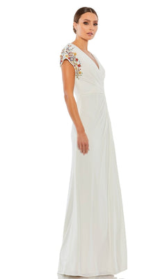 A woman wearing the Mac Duggal 55709 Cap-Sleeve Long Formal Gown with floral shoulder embroidery, standing against a white background.