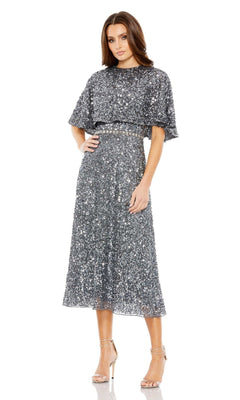 A woman stands wearing the Mac Duggal 5577 Caped Midi Semi-Formal Dress with short sleeves and a belted waist, paired with strappy high-heeled sandals.