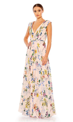 A woman wears the Mac Duggal 55829 Long Floral-Print Formal Dress, a sleeveless light pink V-neck gown with vibrant floral designs, shown standing against a white background.