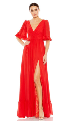 A woman models the Long Formal Dress 55867 by Mac Duggal, a floor-length bright red gown with short puffed sleeves, v-neckline, high slit, and ruffled hem, paired with strappy high-heeled sandals.
