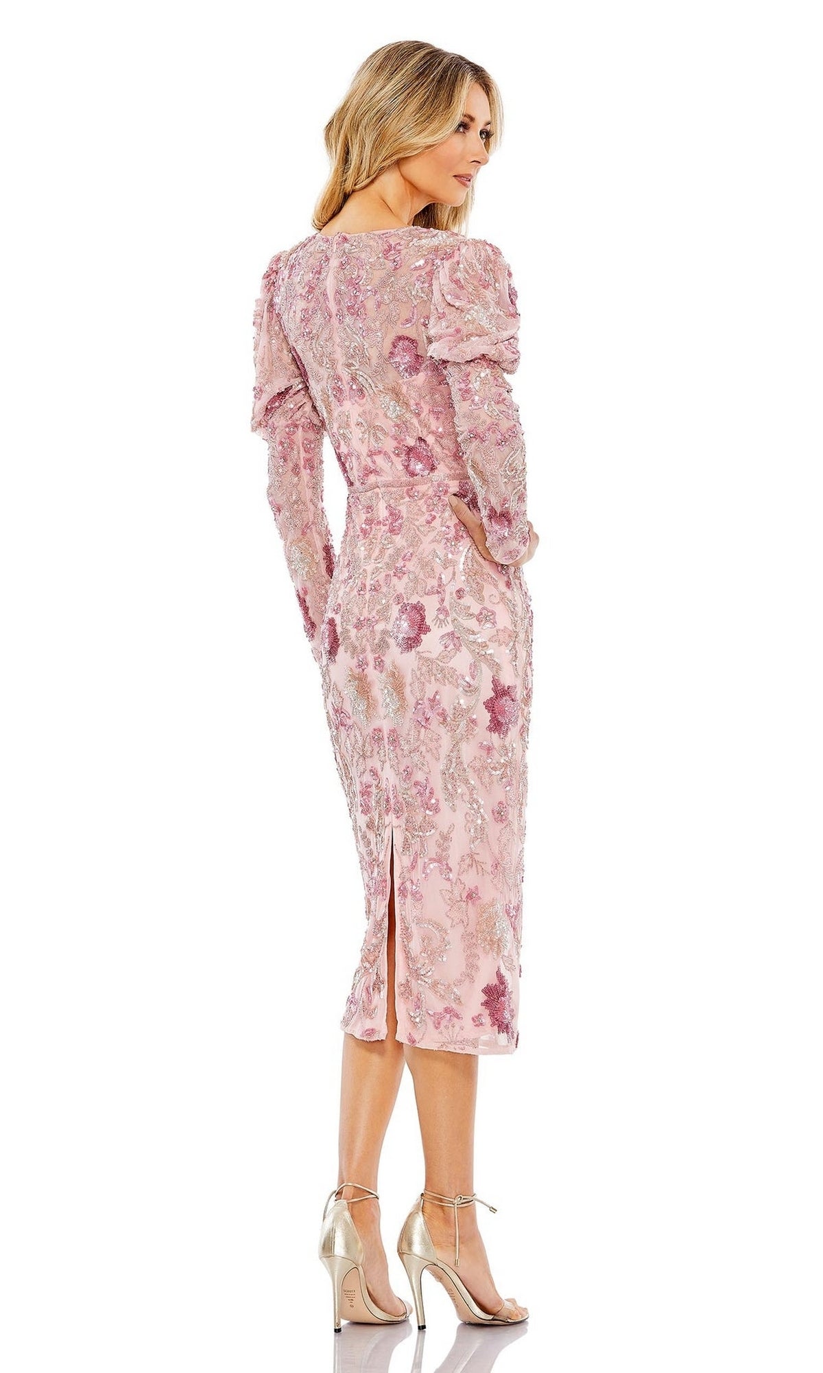 A woman in the Short Semi-Formal Dress 5590 by Mac Duggal, featuring pink floral patterns, long sleeves, a beaded waistband, and metallic heels, stands against a white background.
