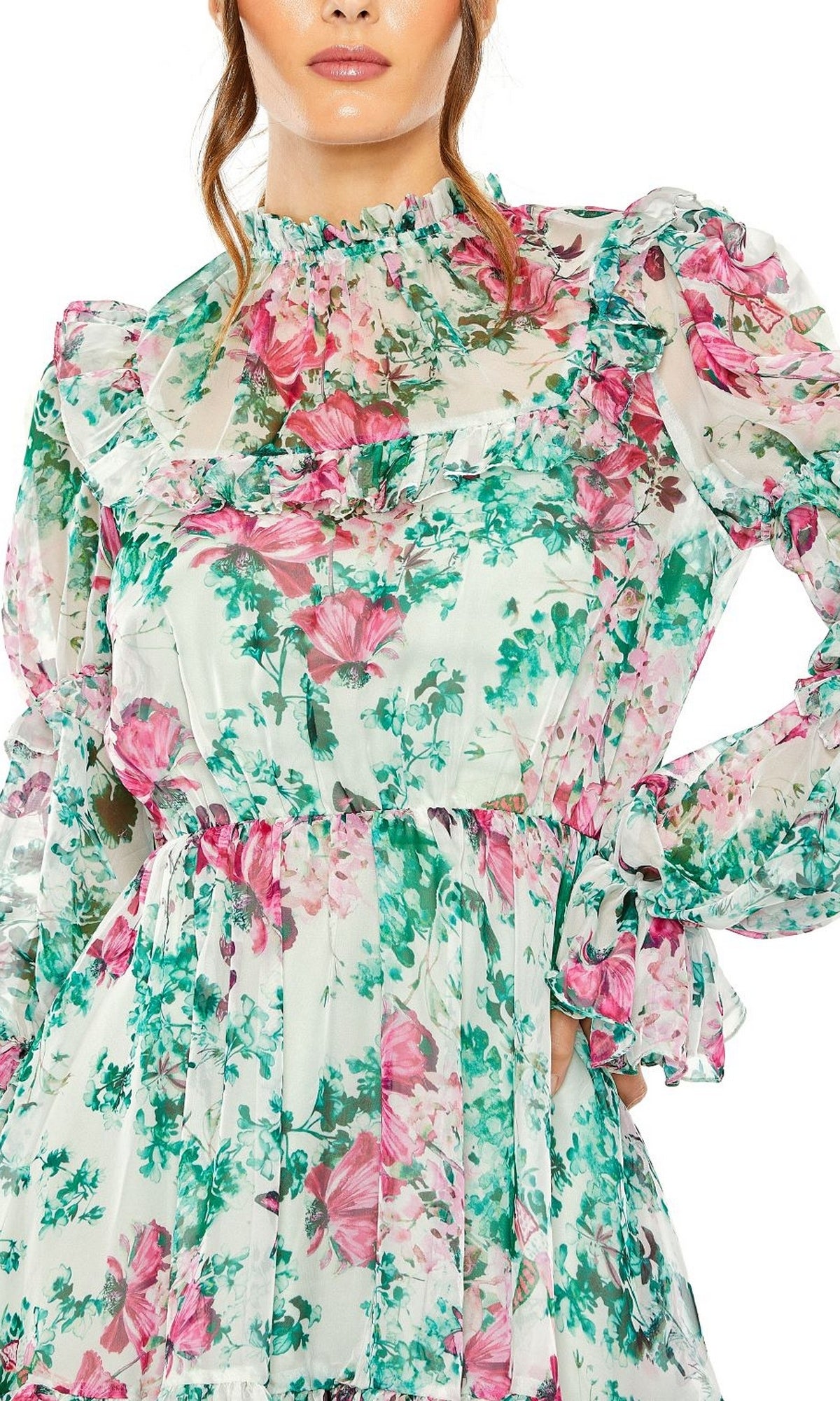 A woman wears the High-Neck Print Party Dress 56008 by Mac Duggal, featuring long sleeves and a pink and green floral print on sheer, lightweight fabric.