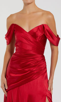 A woman wears the Mac Duggal 56037 Off-the-Shoulder Prom Dress, showcasing a fitted silhouette with draped detailing and a ruched waist for an elegant look.