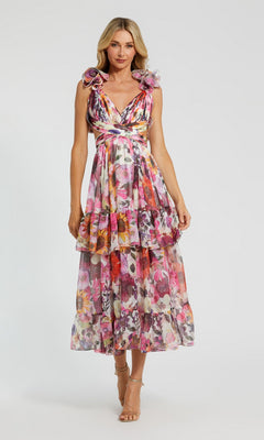 A woman models the Mac Duggal 56048 Midi Wedding Guest Dress in White Multi—a sleeveless, v-neck chiffon dress with floral print and layered ruffles—against a plain background.
