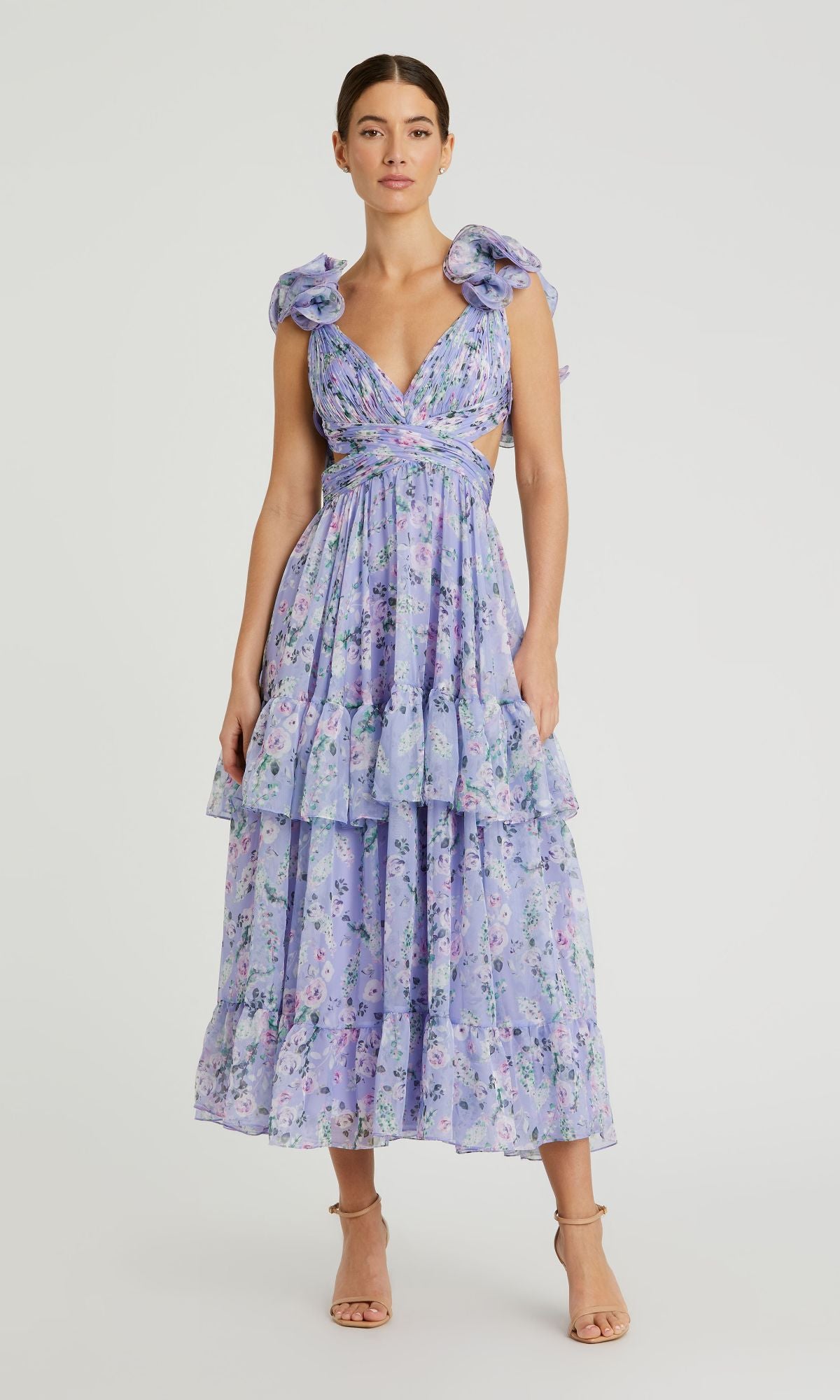 A woman wears the Mac Duggal 56049 Midi Lilac Print Party Dress, featuring ruffled shoulder straps, open sides, a sleeveless tiered design, and pairs it effortlessly with nude heeled sandals.