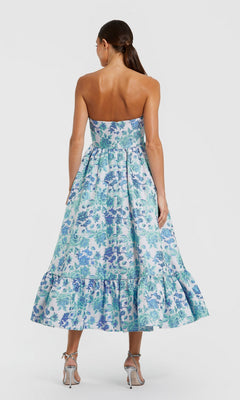Model facing away in the Mac Duggal 56092 Midi Wedding Guest Dress, featuring a strapless blue and green floral pattern with a ruffled hem, styled with silver heels—an elegant pick for weddings.