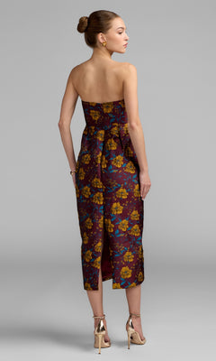 Woman in a strapless, maroon floral-print Midi Floral Wedding Guest Dress: Mac Duggal 56097 with gold heels, standing on a gray background, facing away from the camera.