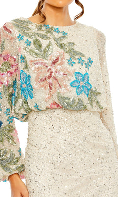 A woman wears the Mac Duggal 5615 Beaded Long Sleeve Formal Dress in cream, adorned with blue, pink, and green floral sequin embroidery on the top.