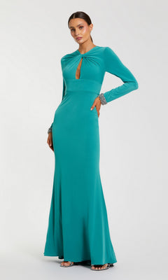 A woman stands against a plain white background wearing the Mac Duggal 56150 long formal dress—a floor-length, long sleeve evening gown in teal—styled with silver bracelets and silver open-toed heels. The dress features a front keyhole cutout.