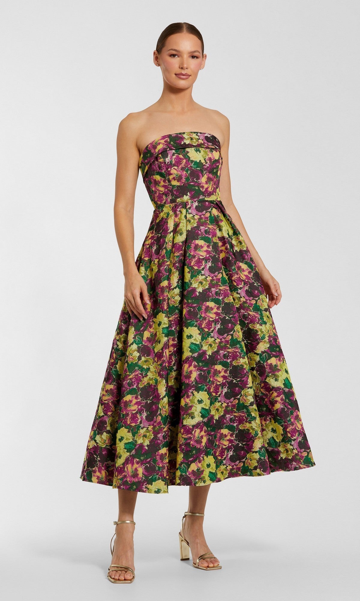 A woman stands against a plain background in neutral heels, wearing the Mac Duggal 56165 Tea-Length Party Dress in Plum Multi—a strapless floral party dress with a full skirt.