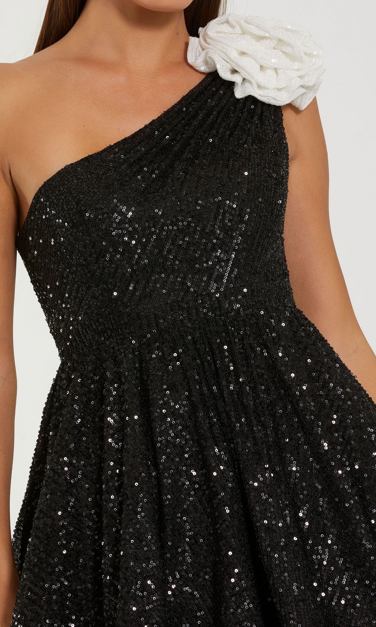 Woman wearing the Mac Duggal 56179 short semi-formal dress—a black sequin one-shoulder mini dress with a white textured flower on the shoulder.