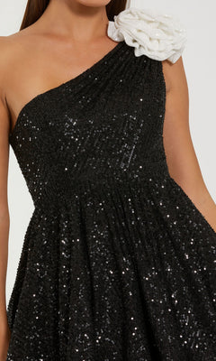Woman wearing the Mac Duggal 56179 short semi-formal dress—a black sequin one-shoulder mini dress with a white textured flower on the shoulder.