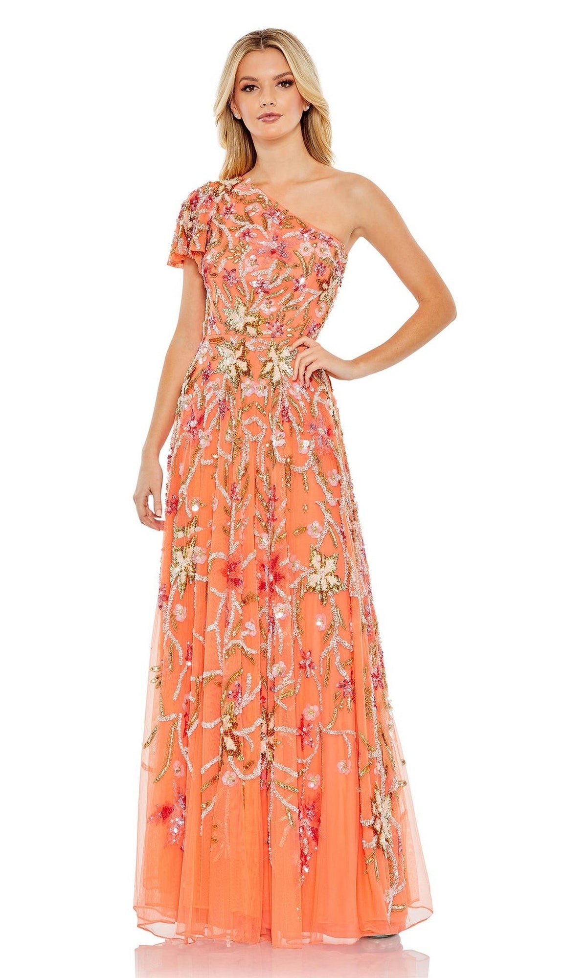 A woman stands against a white background wearing the Mac Duggal Long Formal Dress 5617, a floor-length, one-shoulder coral gown with floral beading and embellishments.