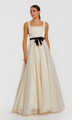 An elegant woman models the Mac Duggal 56185 long formal dress in ivory—a sleeveless, floor-length gown featuring black polka dots and a black bow belt—as she poses against a plain white background.
