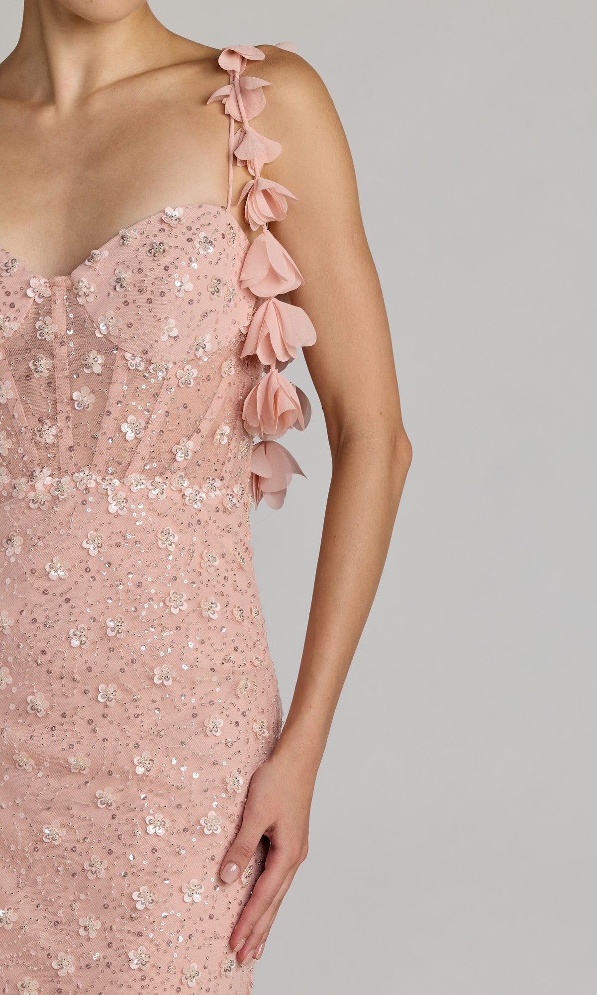 A person wearing the Mac Duggal 56259 Long Formal Dress, featuring light pink sequins and floral appliqué straps, shown from shoulders to mid-thigh against a plain background.