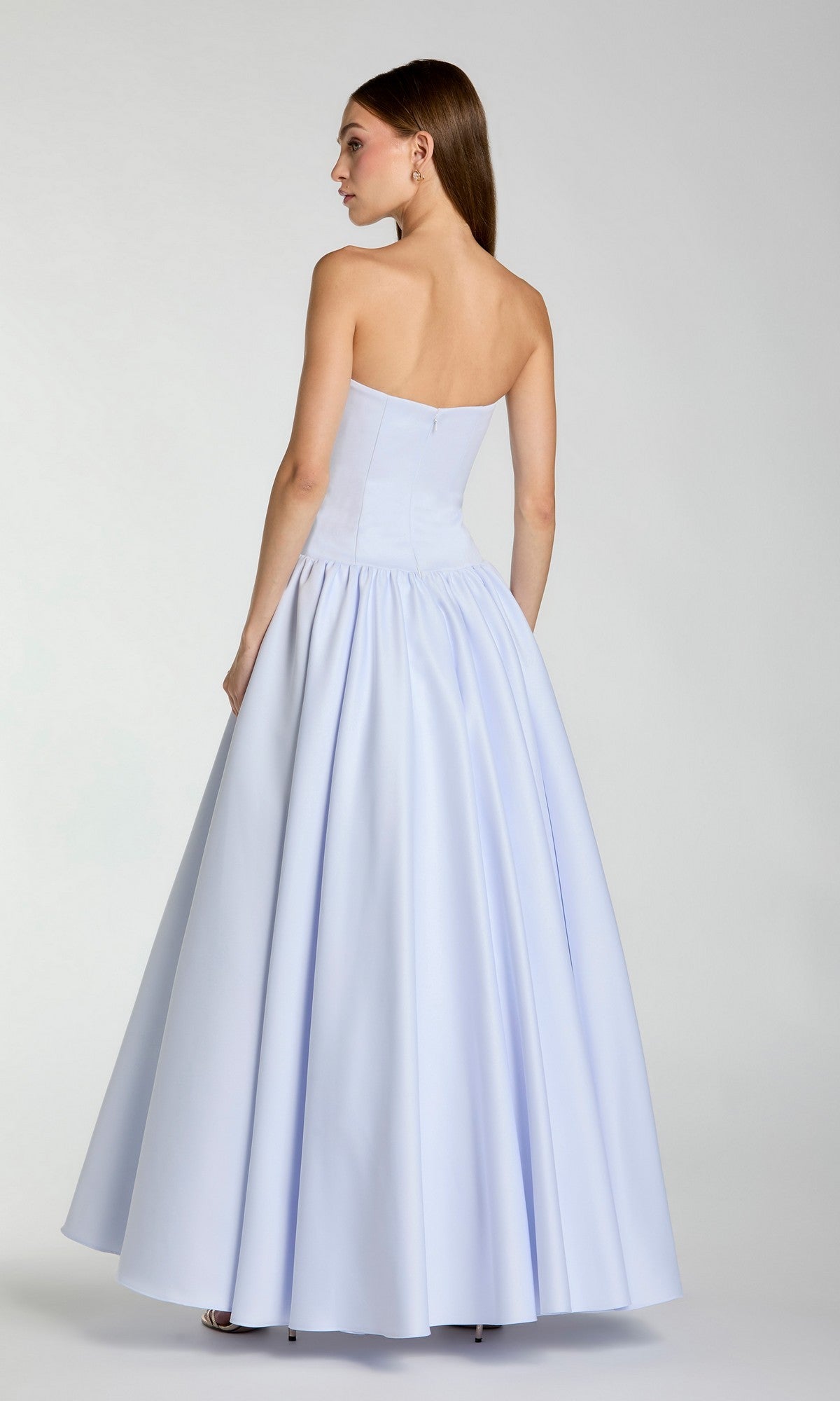 A woman is standing with her back to the camera against a plain background, wearing the Mac Duggal 56270 long formal dress—an A-line, floor-length evening gown in light blue with a strapless neckline.