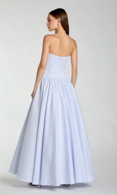 A woman is standing with her back to the camera against a plain background, wearing the Mac Duggal 56270 long formal dress—an A-line, floor-length evening gown in light blue with a strapless neckline.