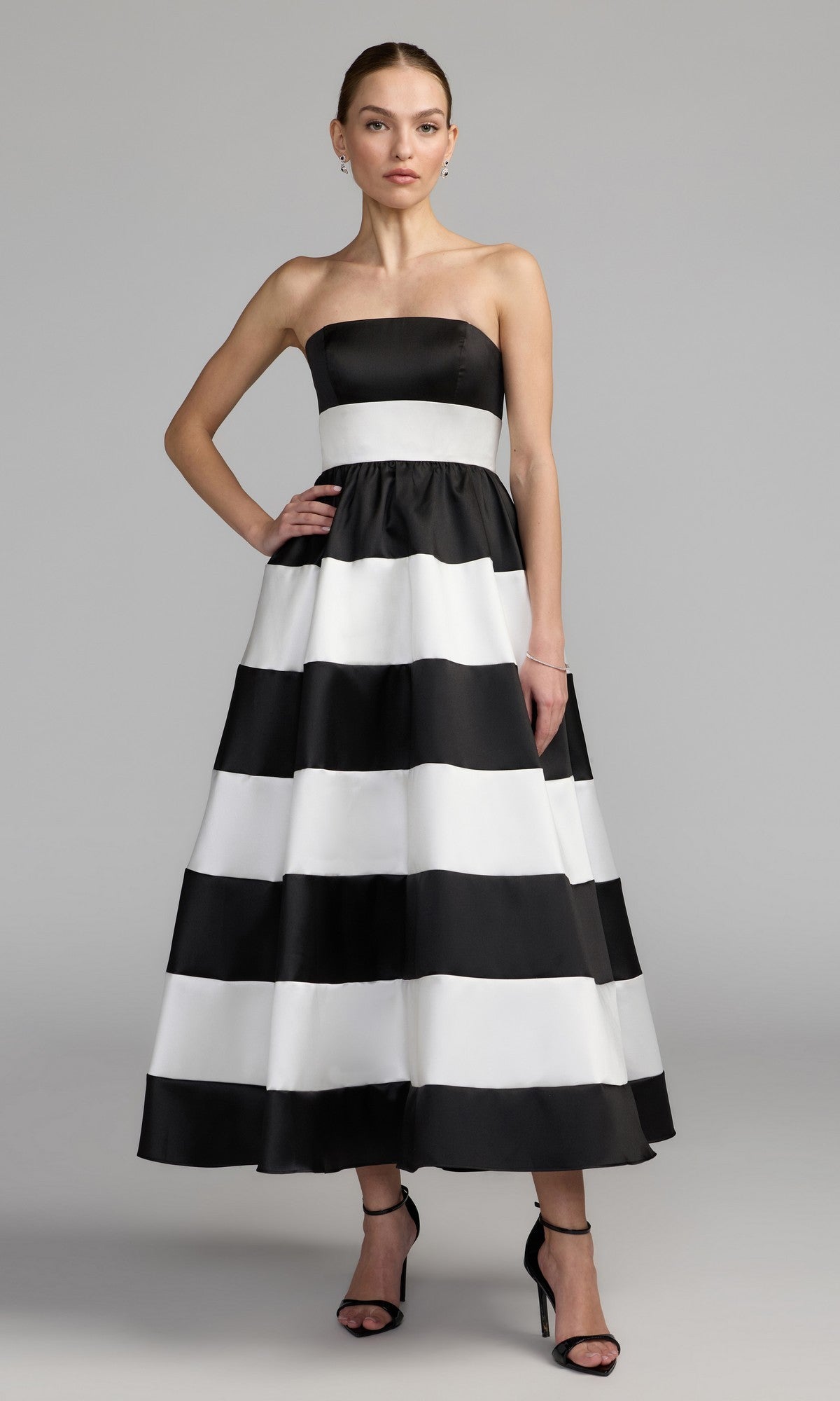 A woman wearing the Mac Duggal 56281 Tea-Length Party Dress in Black Ivory, featuring a chic strapless neckline and elegant ankle-length silhouette, paired with black high-heeled sandals—the ideal strapless midi party dress for any special occasion.