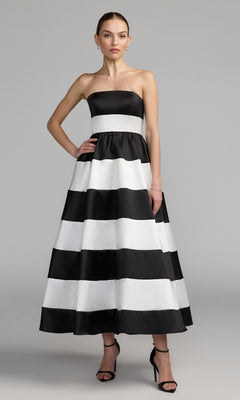 A woman wearing the Mac Duggal 56281 Tea-Length Party Dress in Black Ivory, featuring a chic strapless neckline and elegant ankle-length silhouette, paired with black high-heeled sandals—the ideal strapless midi party dress for any special occasion.