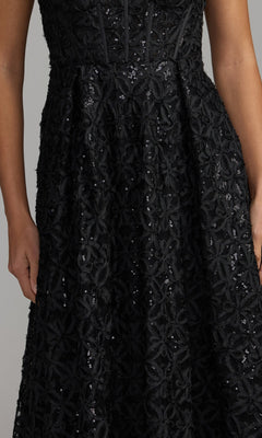 A person wearing the Mac Duggal 56286 long formal dress in black lace with floral patterns and sequins, shown from the shoulders to the knees.