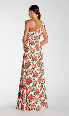 A woman stands with her back to the camera, wearing the Long Formal Dress: Mac Duggal 56297—a one-shoulder gown adorned with a vivid red and pink rose floral print—set against a plain white background.