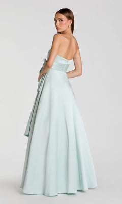A woman wearing the Mac Duggal 56318 long formal dress—strapless, satin, light blue, and floor-length—stands facing away and glances over her shoulder against a plain light background.