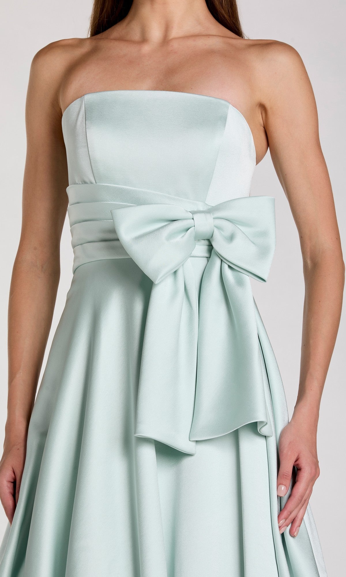 A woman wearing the Mac Duggal 56318 long formal dress—a strapless satin gown in light blue featuring a wide waistband and a large bow on the front, exuding elegant style.