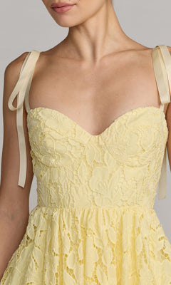 A woman models the Mac Duggal 56319 Midi Party Dress in pale yellow lace with ribbon shoulder straps, shown from neck to waist against a plain background.